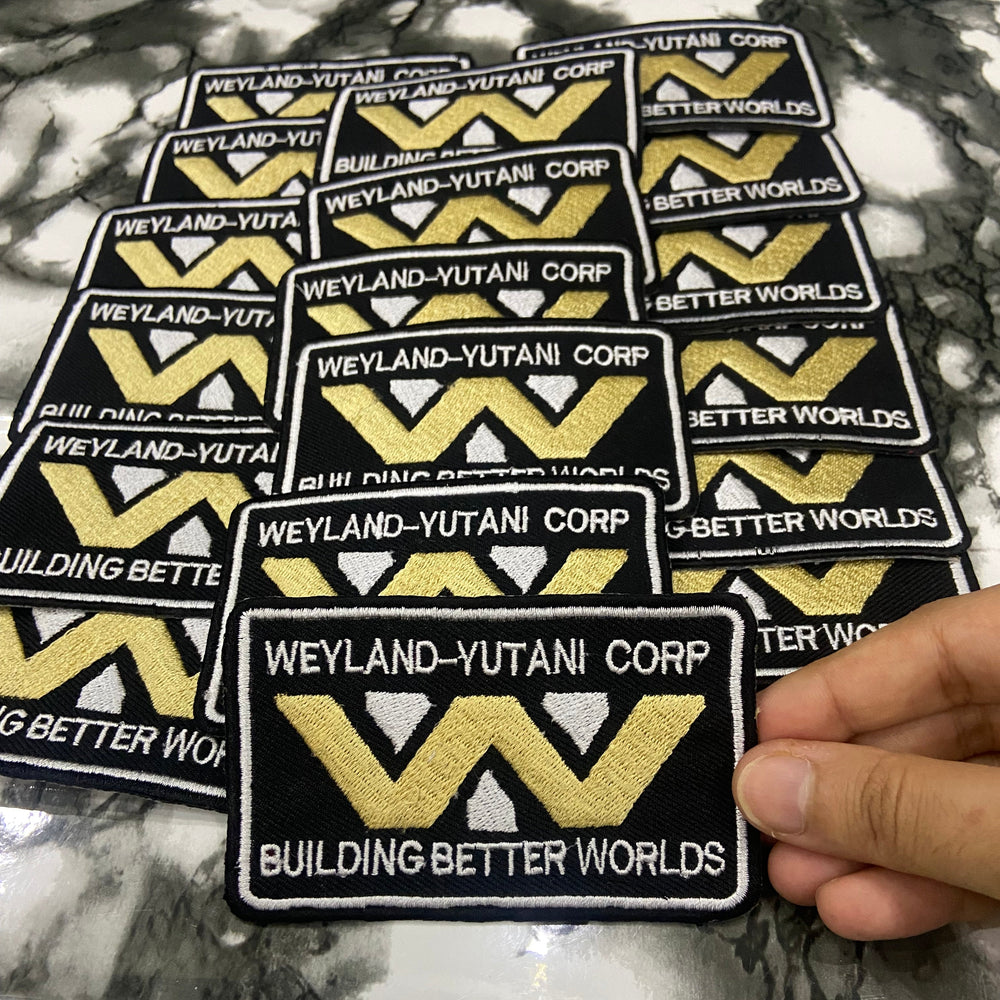 Collection of 'Weyland-Yutani Corp' patches on a marble surface.