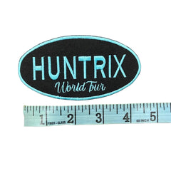 Huntrix logo with a ruler for scale on a gray background