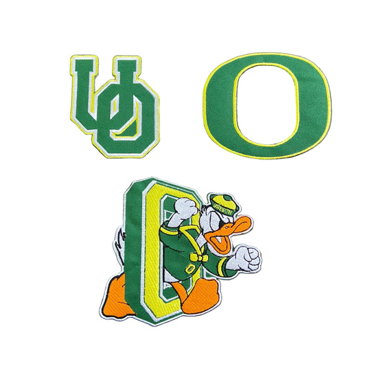 Three green and yellow embroidered patches on a dark gray background: a large letter O, a stylized UO logo, and a donald duck in O.