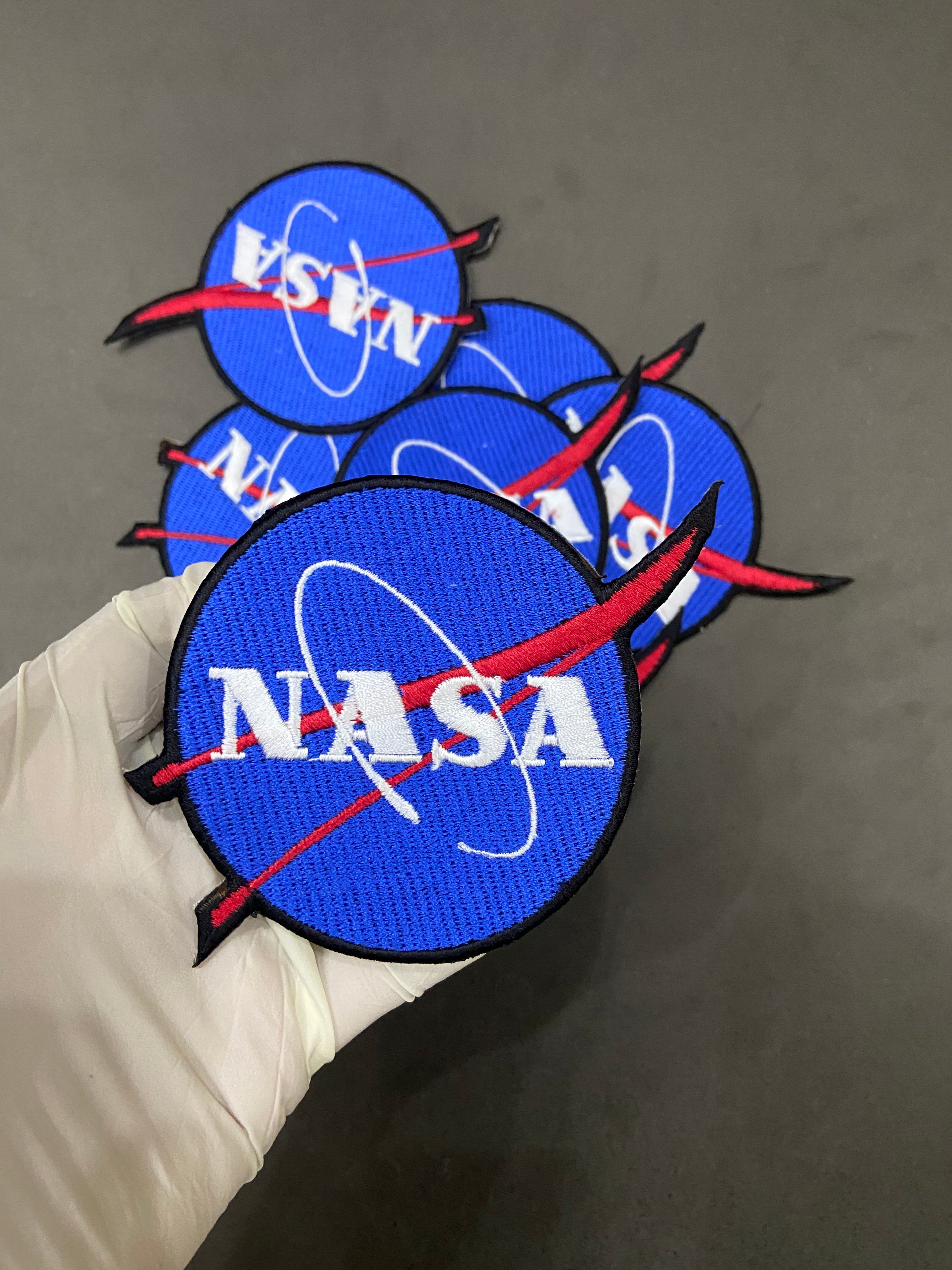 Multiple NASA patches on a dark background
