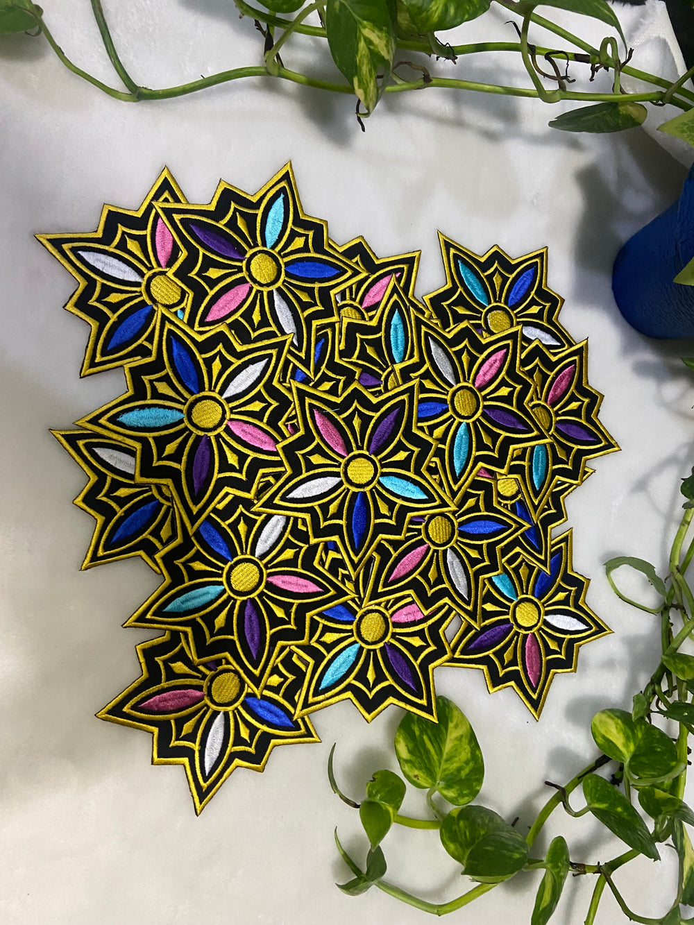 Colorful geometric design on a white surface with green leaves.