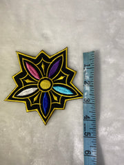 Decorative patch with a star-like design on a textured surface, measured against a ruler.