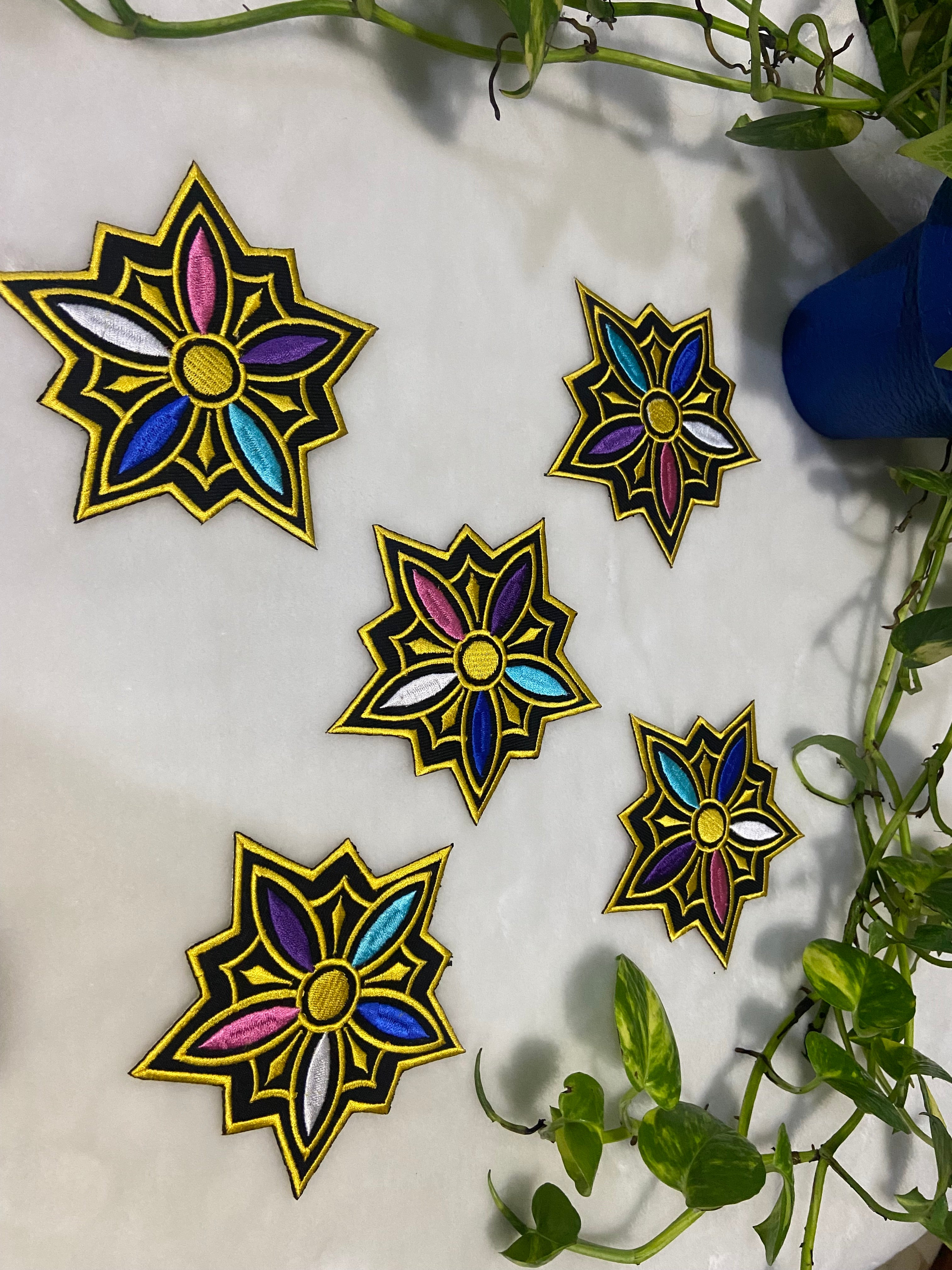 Colorful star-shaped decorations on a white surface with green leaves in the background