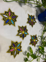 Colorful star-shaped decorations on a white surface with green leaves in the background