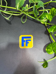 Yellow and blue logo on a dark background with green leaves in the foreground