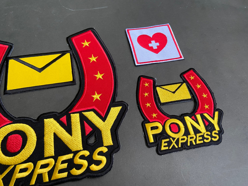 Pony Express patches with a heart and cross patch on a dark background