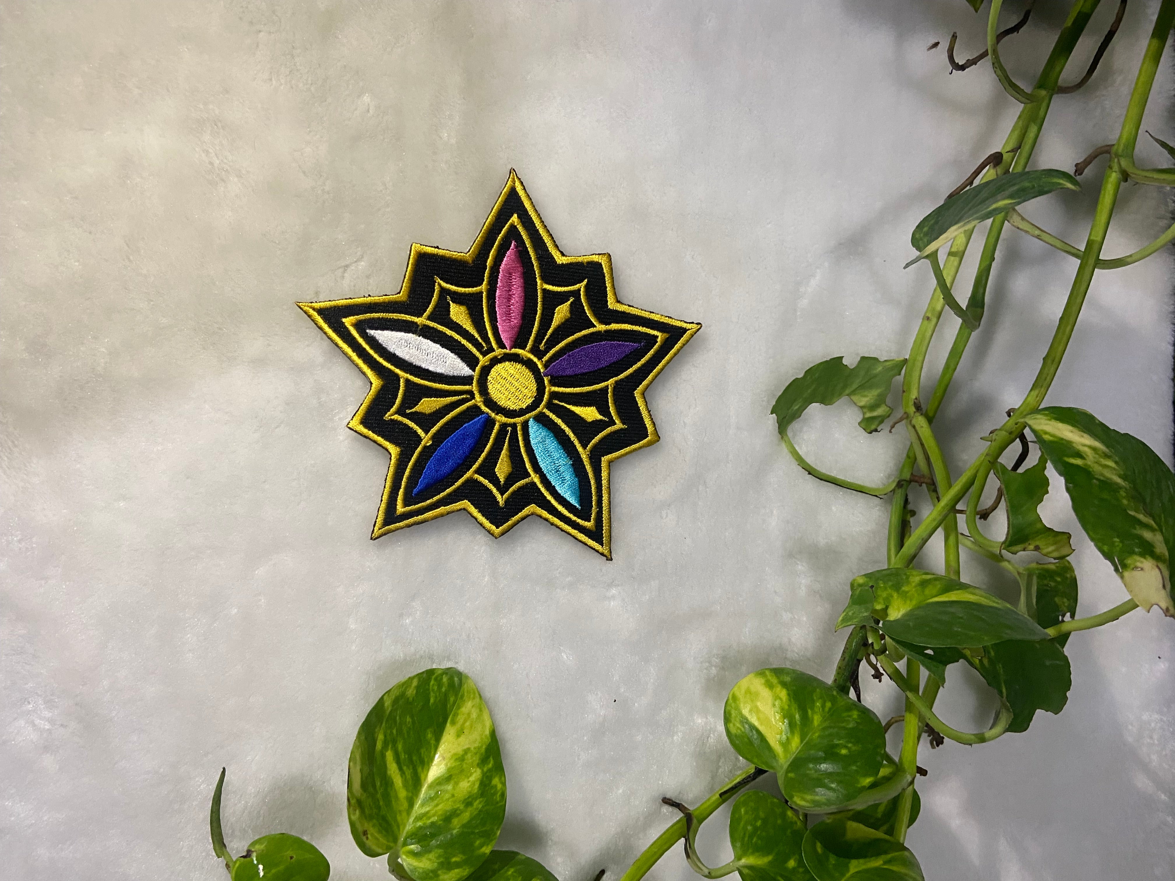Colorful star-shaped pin on a textured surface with green leaves