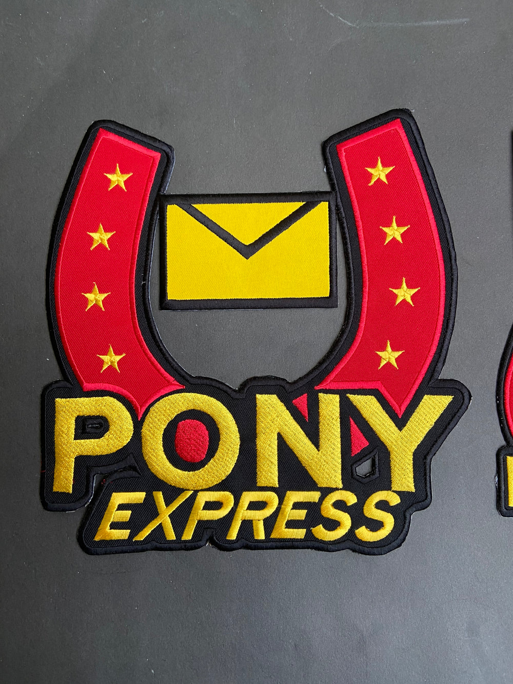 Pony Express logo patch with red, yellow, and black colors on a dark background
